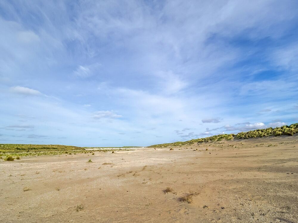 Weids duinlandschap met strandvlakte en wolkenlucht aan de kust bij 's-Gravenzande